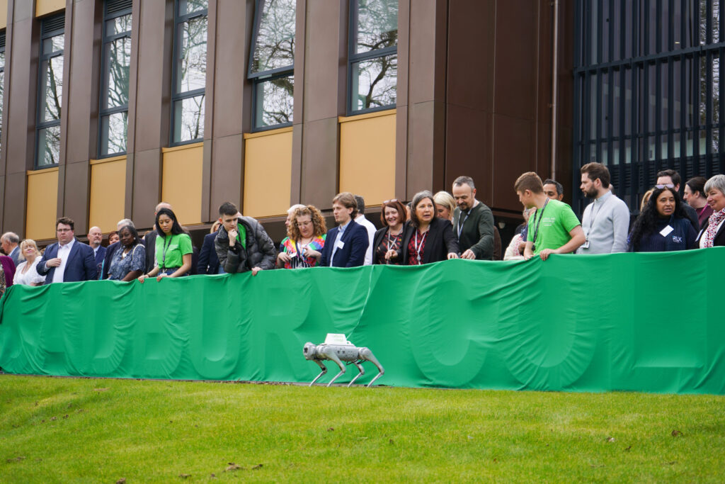 A robotic dog uncovers the Cadbury College sign at the campus launch
