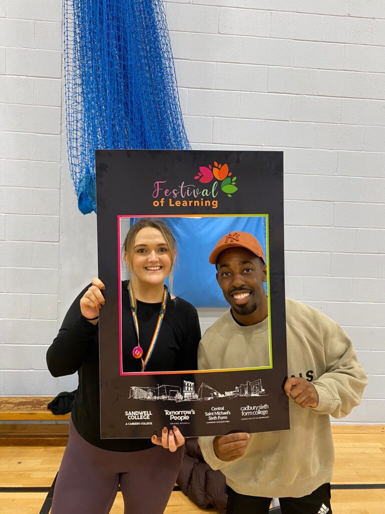 Rosie and Khalid smiling with a Festival of Learning frame