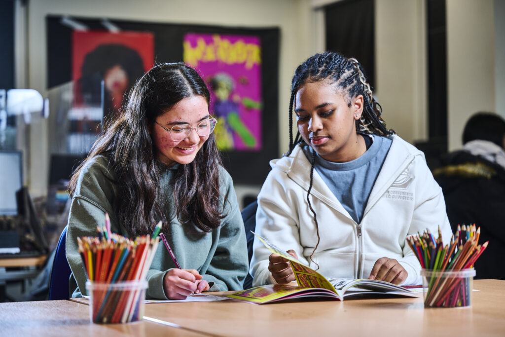 Two female students looking through a book together