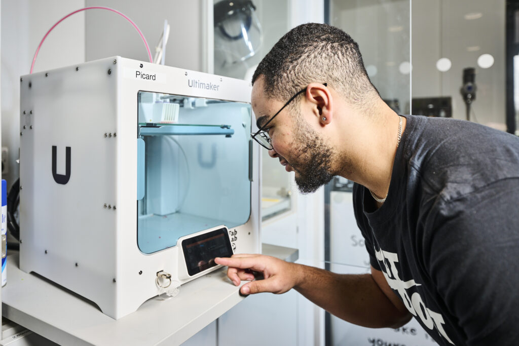 Student with 3D machine pressing a button