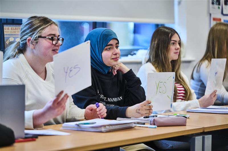 Students in a classroom holding up 'yes' or 'no' signs