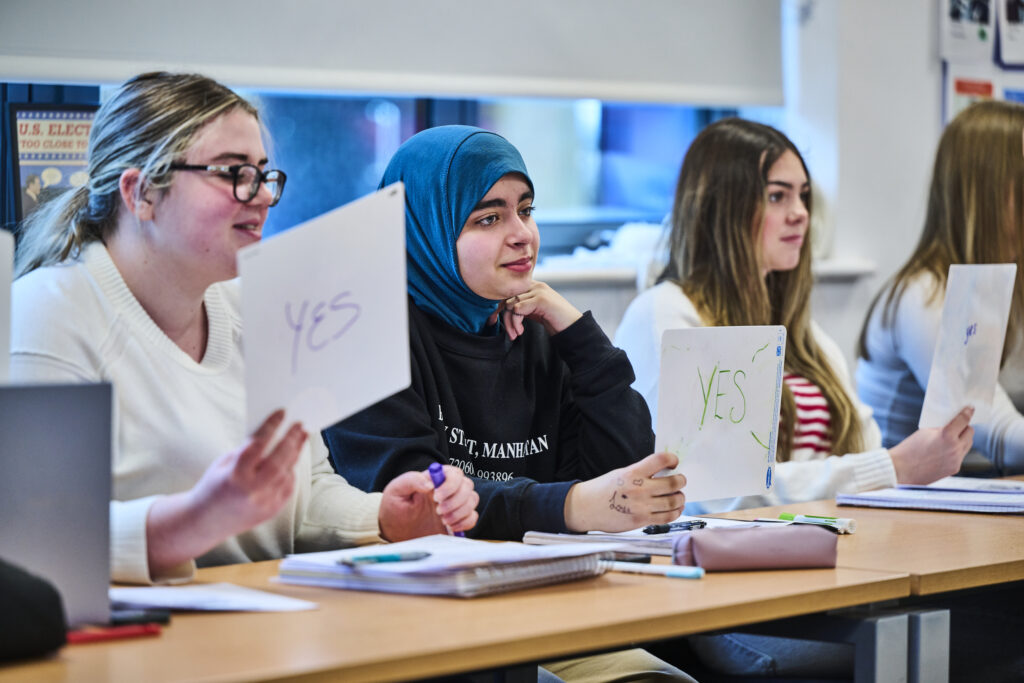 Students in a classroom holding up yes/no cards