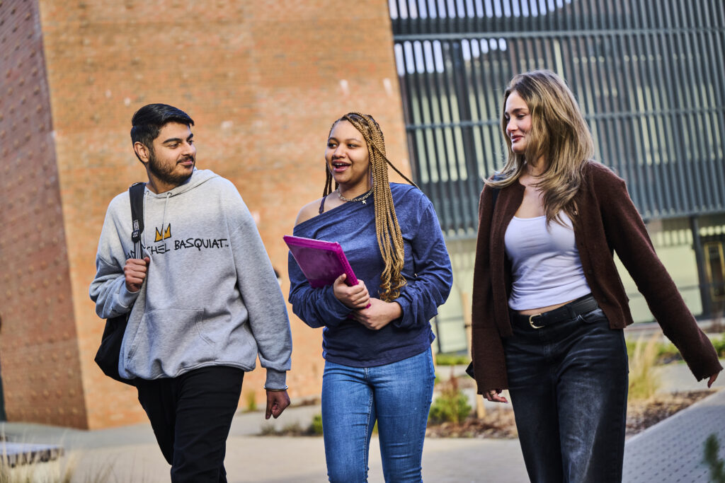 Three students walking through the courtyard with their bags