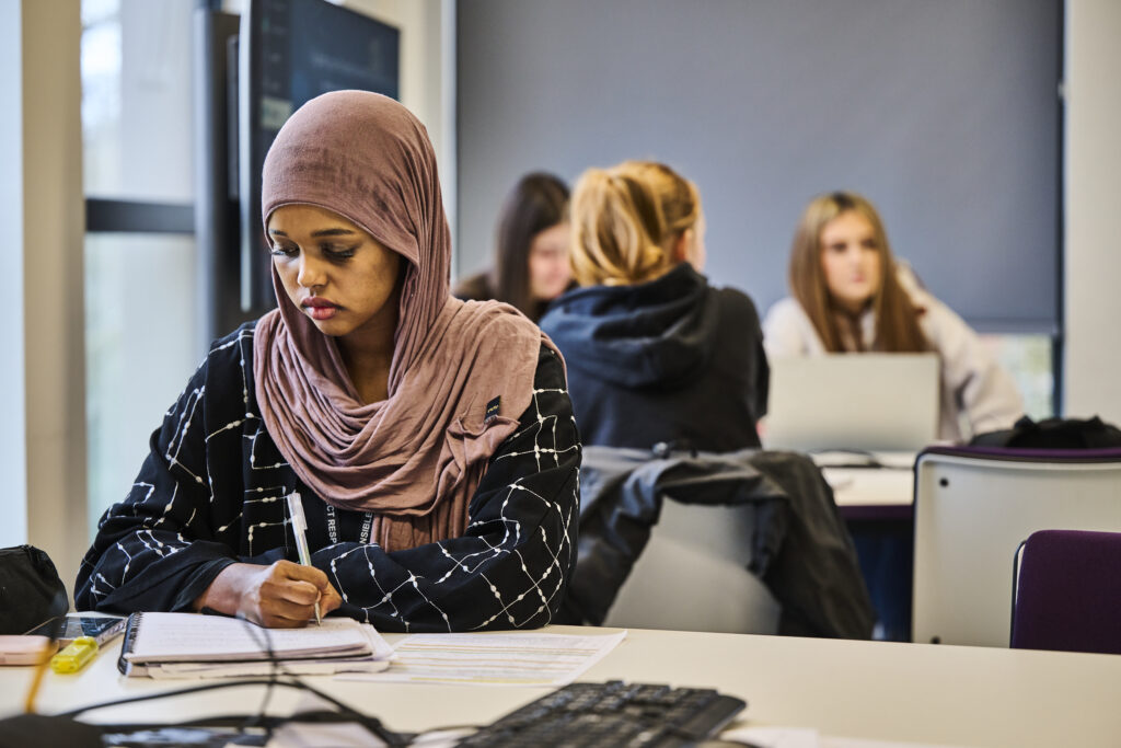 Student in foreground working with students working in the background