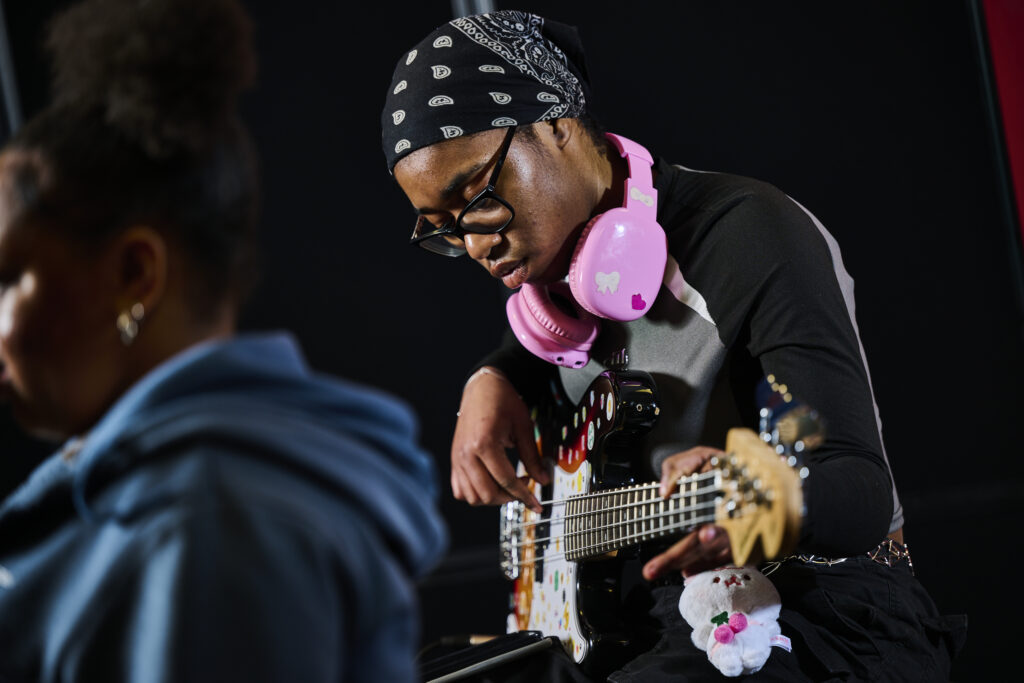 Student playing the guitar with headphones on