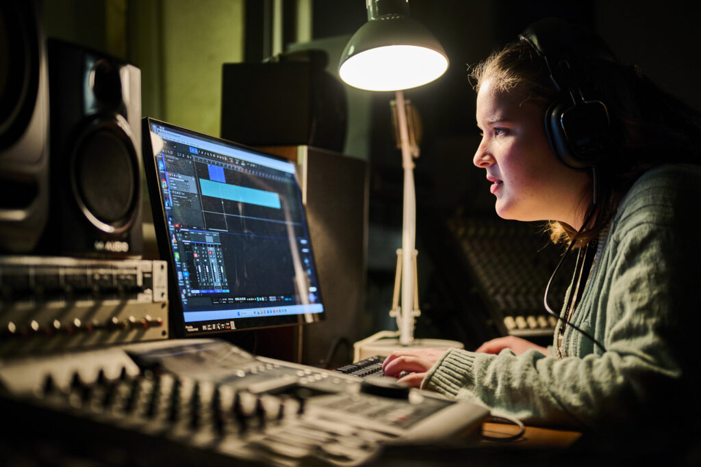 Music production student with mixer and screen